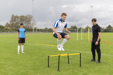 Trainer beim Training mit Fußballspielern auf dem Sportplatz, lizenzfreies Stockfoto