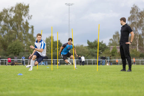 Coach exercising with soccer players on sports field stock photo