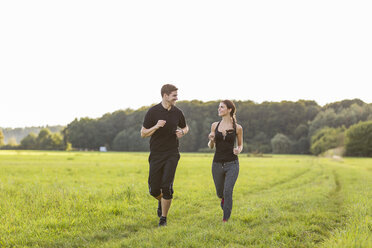 Mann und Frau joggen auf einem Feld - SHKF000407