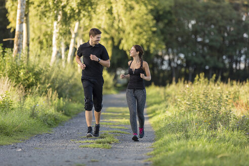 Mann und Frau joggen auf einem Feldweg - SHKF000409