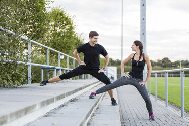 Man and woman stretching on sports field - SHKF000415
