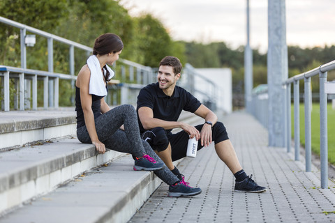 Sportlicher Mann und Frau unterhalten sich auf einem Sportplatz, lizenzfreies Stockfoto