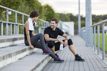 Sportive man and woman talking on sports field - SHKF000417