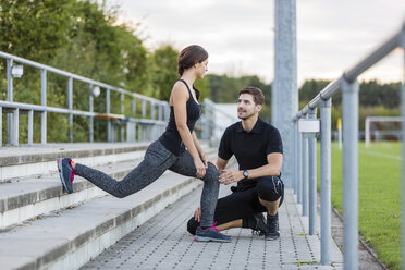 Mann betrachtet Frau, die auf einem Sportplatz trainiert - SHKF000419