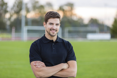 Porträt eines lächelnden Mannes auf einem Sportplatz, lizenzfreies Stockfoto