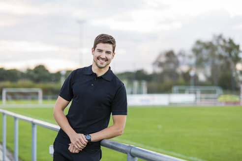 Porträt eines lächelnden Mannes auf einem Sportplatz - SHKF000422