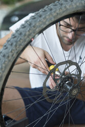 Junger Mann, der in einer Werkstatt ein Rad an einem Fahrrad montiert - SKCF000036