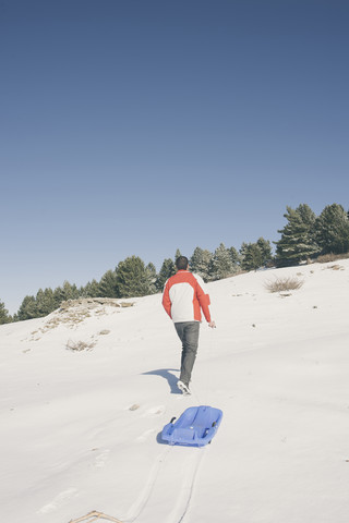 Spanien, La Molina, Mann mit Plastikschlitten, lizenzfreies Stockfoto