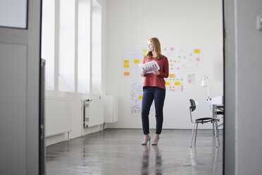 Junge Frau im Büro liest Tabellen - RBF003916