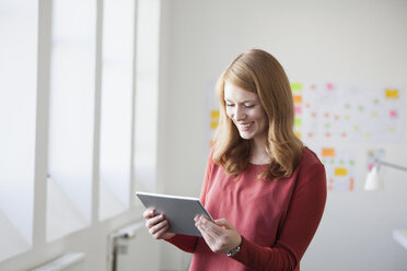 Junge Frau im Büro mit digitalem Tablet - RBF003917