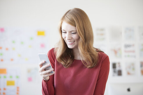 Junge Frau im Büro mit Smartphone - RBF003929