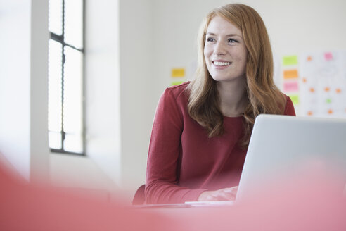 Junge Frau im Büro mit Laptop - RBF003932