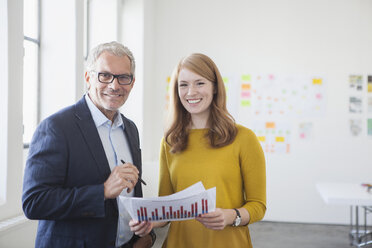 Geschäftsmann und Mitarbeiterin im Büro beim Studium von Infografiken - RBF003951