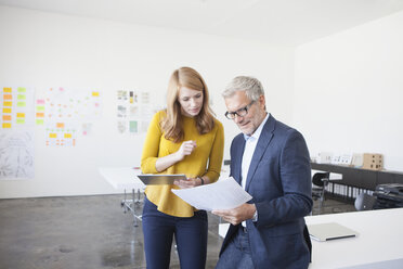 Geschäftsmann und Mitarbeiterin im Büro beim Studium von Infografiken - RBF003953