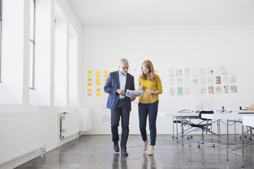 Geschäftsmann und Mitarbeiterin im Büro beim Studium von Infografiken - RBF003954