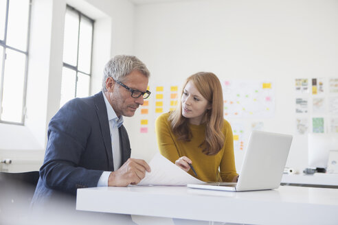 Geschäftsmann und Mitarbeiterin bei der Arbeit im Büro - RBF003961