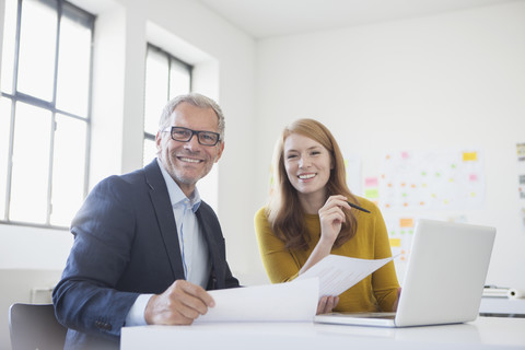 Geschäftsmann und Mitarbeiterin bei der Arbeit im Büro, lizenzfreies Stockfoto