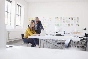 Geschäftsmann und Mitarbeiterin bei der Arbeit im Büro - RBF003963