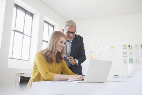 Geschäftsmann und Mitarbeiterin bei der Arbeit im Büro - RBF003964