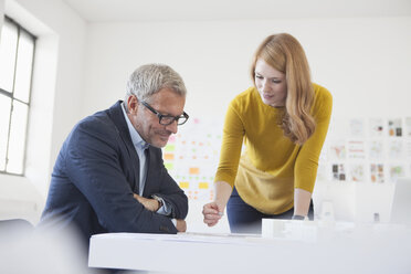 Geschäftsmann und Mitarbeiterin bei der Arbeit im Büro - RBF003970