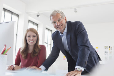 Geschäftsmann und Mitarbeiterin bei der Arbeit im Büro - RBF003973