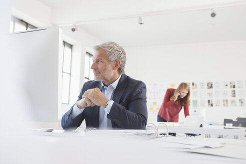 Geschäftsmann und Mitarbeiterin bei der Arbeit im Büro - RBF003975