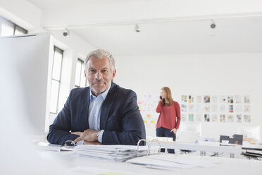 Geschäftsmann und Mitarbeiterin bei der Arbeit im Büro - RBF003976