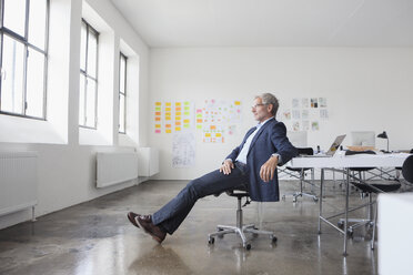 Mature businessman sitting in office, looking to the window - RBF003982