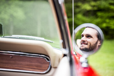 Spiegelung eines lächelnden jungen Mannes im Außenspiegel eines Cabrios - DAWF000446