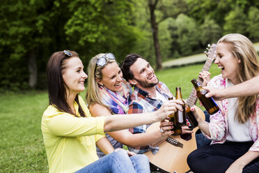 Happy friends clinking beer bottles in park - DAWF000451