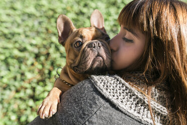 Porträt einer jungen Frau, die eine französische Bulldogge küsst - GEMF000603
