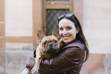 Porträt einer französischen Bulldogge auf den Armen einer lächelnden jungen Frau - GEMF000607
