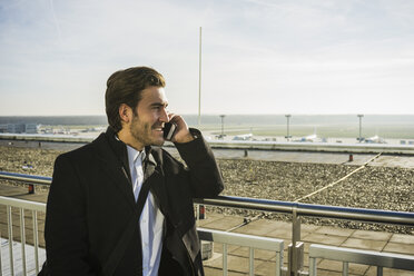 Deutschland, Frankfurt, Junger Geschäftsmann auf dem Flughafen mit Smartphone - UUF006320