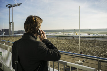 Germany, Frankfurt, Young businessman at the airport using smartphone - UUF006321