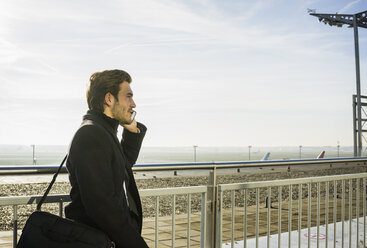 Germany, Frankfurt, Young businessman at the airport using smartphone - UUF006322