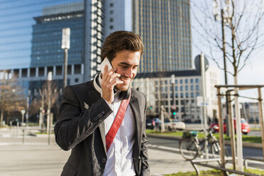 Deutschland, Frankfurt, Junger Geschäftsmann, der mit seinem Handy durch die Stadt läuft - UUF006343