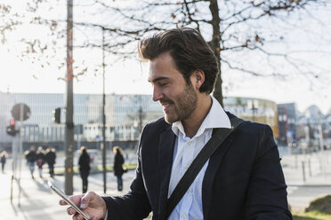 Germany, Frankfurt, Young businessman in the city using mobile phone - UUF006353