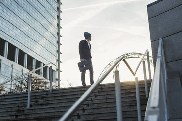 Deutschland, Frankfurt, Junger Geschäftsmann steht auf einer Treppe und schaut weg - UUF006357