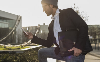 Deutschland, Frankfurt, Junger Geschäftsmann in der Stadt mit Mobiltelefon - UUF006358