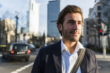 Germany, Frankfurt, Young businessman in the city with bicycle, using mobile phone - UUF006362