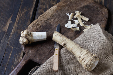 Geschnittener und geschälter Meerrettich auf Holzbrett und Jute - CSF026981