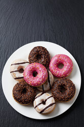 Plate of doughnuts with different icings on slate - CSF027015