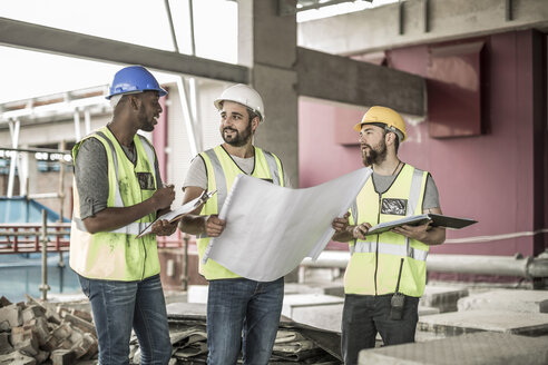 Bauarbeiter diskutieren auf der Baustelle über den Bauplan - ZEF007830