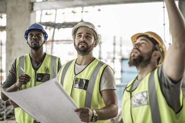 Construction workers discussing building plan in construction site - ZEF007833