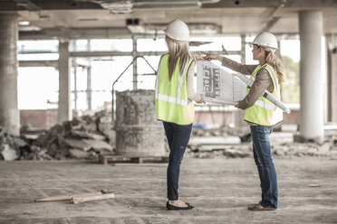 Zwei Frauen in Arbeitsschutzkleidung besprechen einen Bauplan auf einer Baustelle - ZEF007834