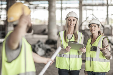 Zwei Frauen in Arbeitsschutzkleidung und ein Bauarbeiter auf einer Baustelle - ZEF007835