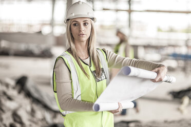 Frau in Arbeitsschutzkleidung mit Bauplan auf einer Baustelle - ZEF007838