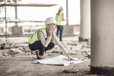 Frau in Arbeitsschutzkleidung telefoniert auf einer Baustelle - ZEF007840