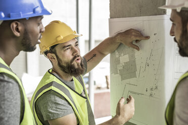 Construction workers discussing building plan in construction site - ZEF007844