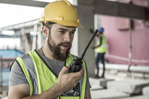 Construction worker with walkie-talkie in construction site - ZEF007846